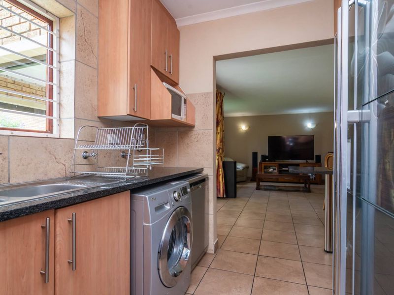 Functional kitchen featuring light wood cabinetry, granite countertops, and tiled flooring, with a convenient layout flowing into the adjacent living area.