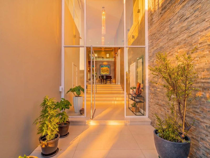 Modern entrance featuring a striking stone-clad wall, expansive floor-to-ceiling glass panels, and a contemporary pivot door leading into a bright, welcoming foyer.