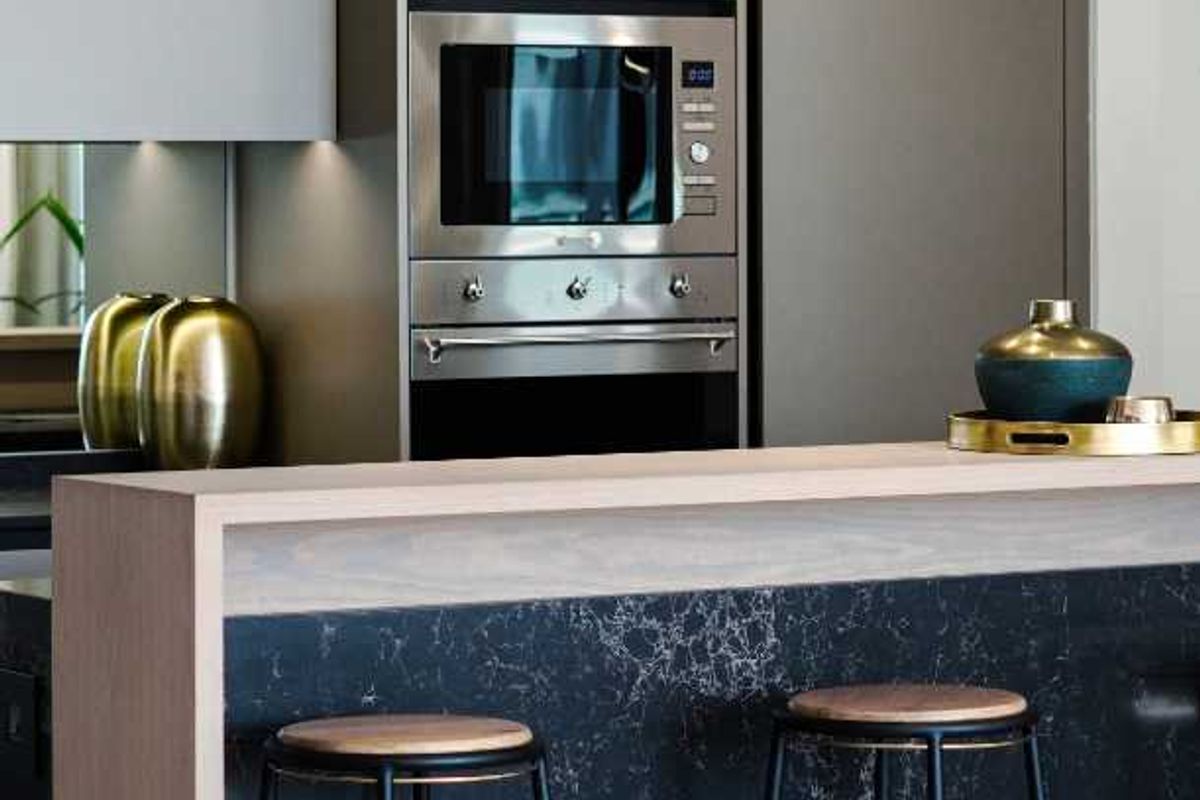 Modern kitchen featuring sleek cabinetry, built-in oven and microwave, and a striking black marble-look breakfast bar island.