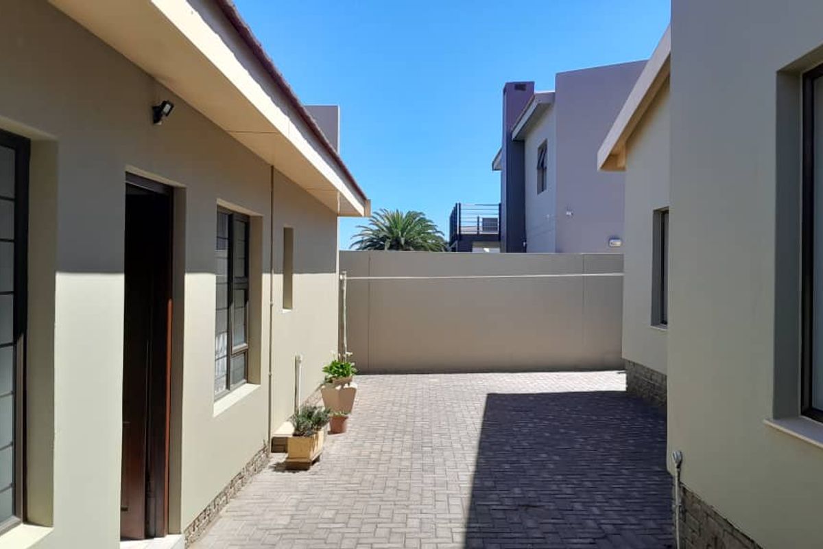 A neat, paved rear courtyard area situated between two sections of the property, featuring clean boundary walls and secure window fittings.