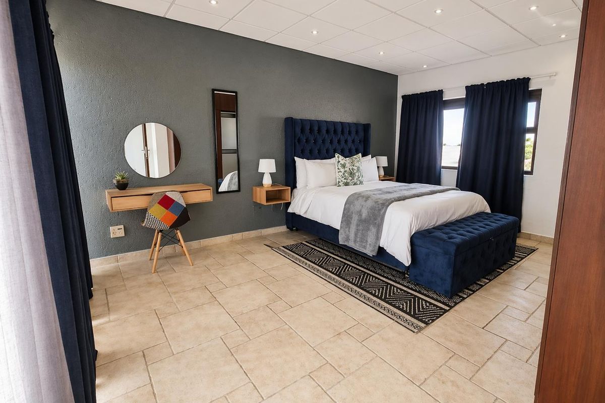 Spacious bedroom featuring tiled flooring, recessed ceiling lighting, and a neutral color palette with a dark accent wall.