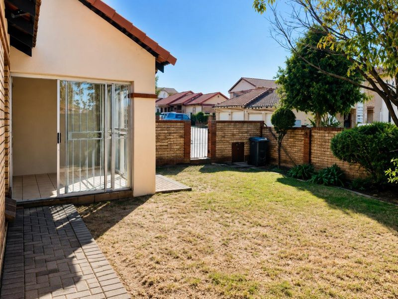 A private rear garden featuring a paved walkway, sliding door access to the home, and a secure brick boundary wall.