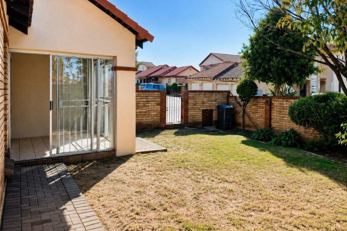 A private rear garden featuring a paved walkway, sliding door access to the home, and a secure brick boundary wall.