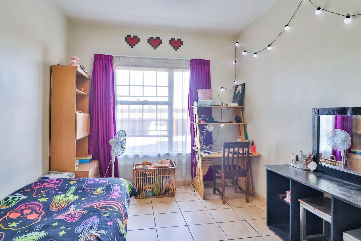 A functional bedroom featuring tiled flooring and a large window, providing natural light and a practical layout for a comfortable living space.