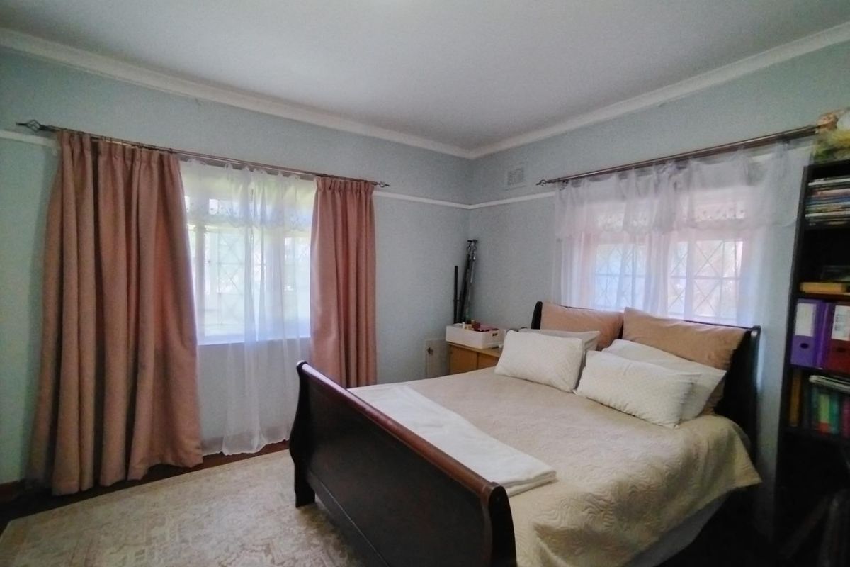 A well-proportioned bedroom featuring classic picture rails, decorative cornicing, and dual aspect windows that provide natural light.