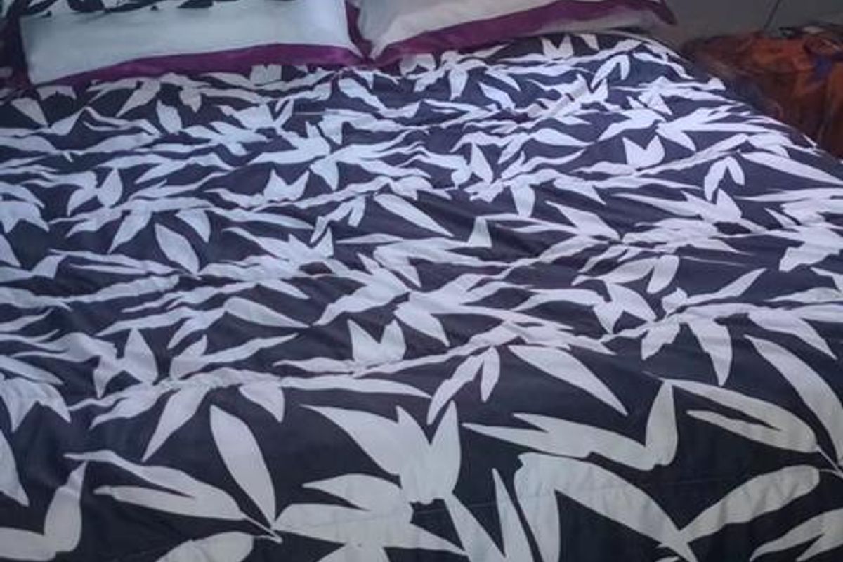 A compact bedroom featuring tiled flooring and a single window, providing a functional space for rest.