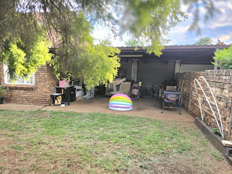 A covered outdoor patio area with brick walls and paved flooring, providing a functional space for outdoor living and storage.