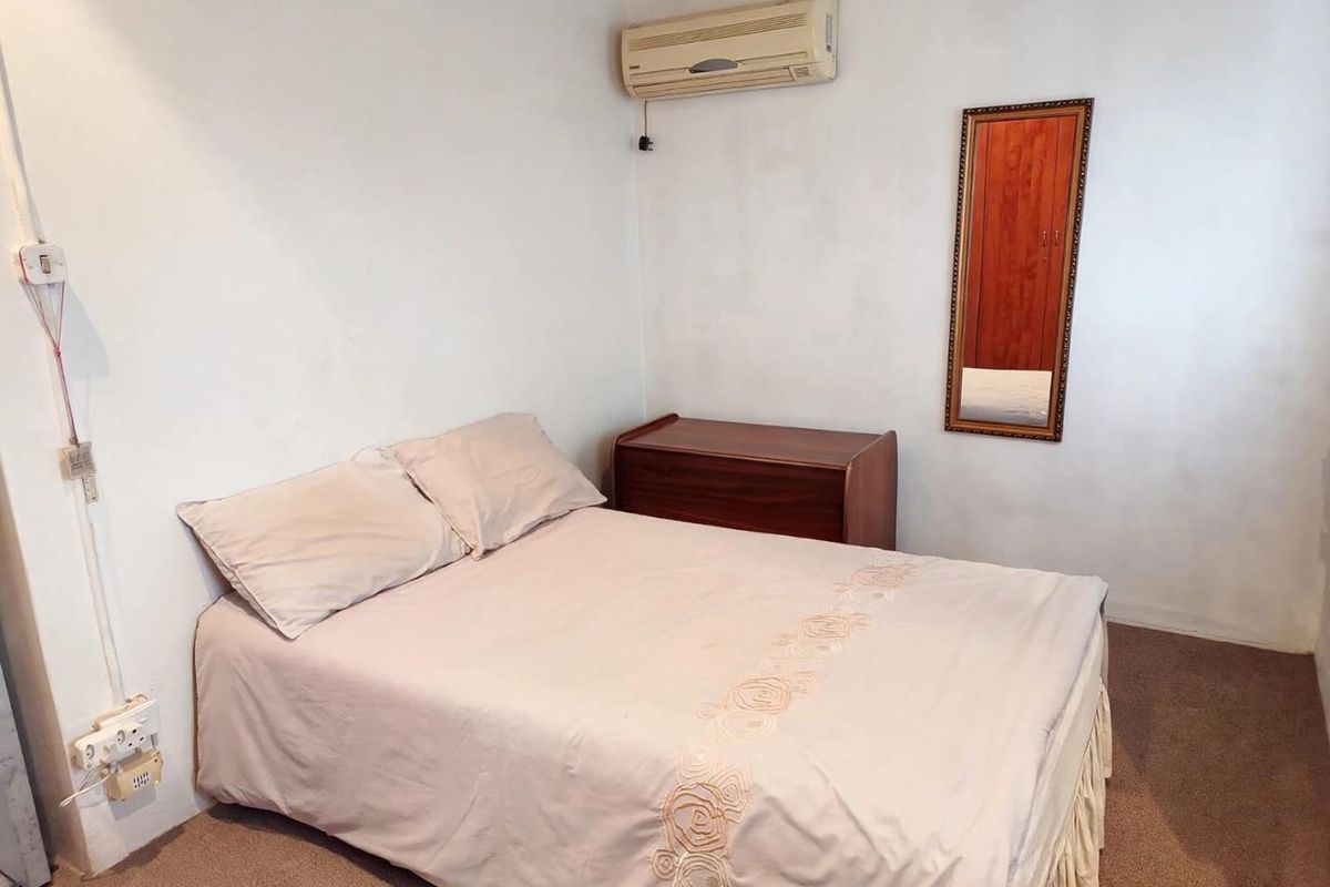 A compact bedroom featuring carpeted flooring and a wall-mounted split-system air conditioning unit.