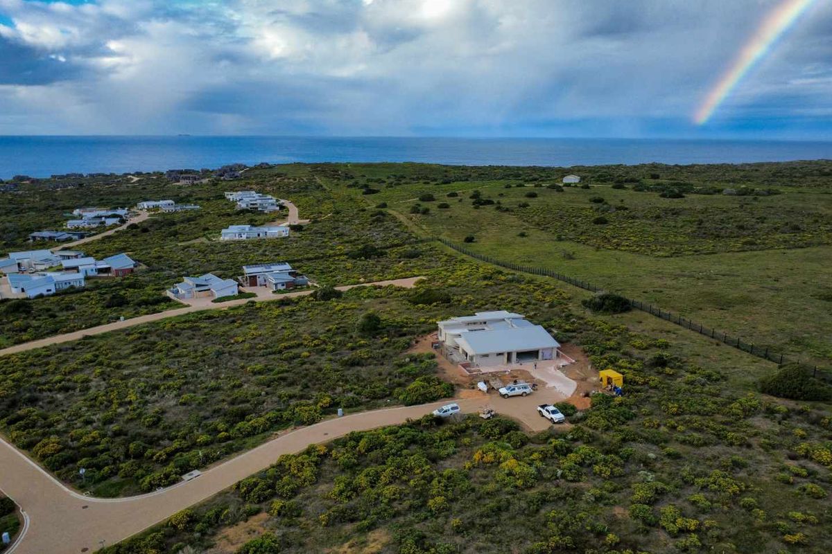 Aerial view of a residential property under construction, situated in a coastal estate with expansive natural landscape and ocean views.