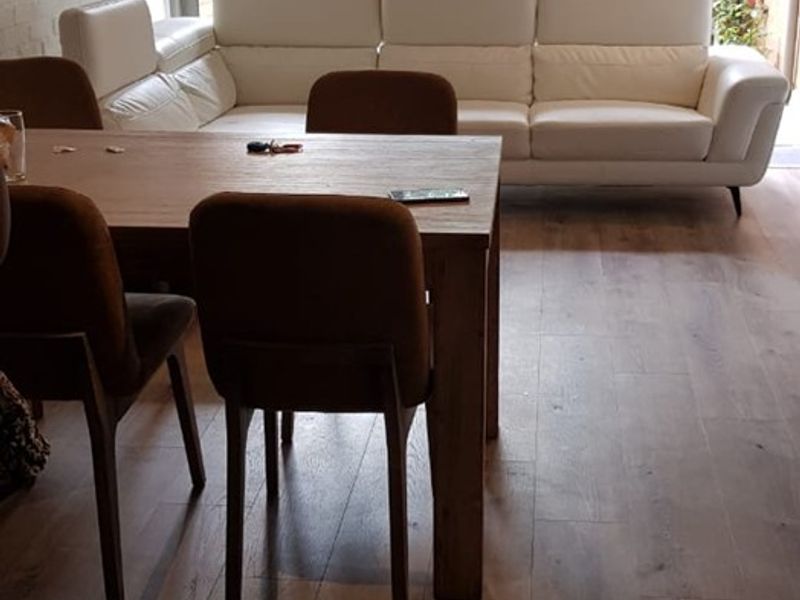 Open plan living and dining area featuring modern laminate flooring, exposed brick wall, and large sliding glass doors leading to an outdoor space.