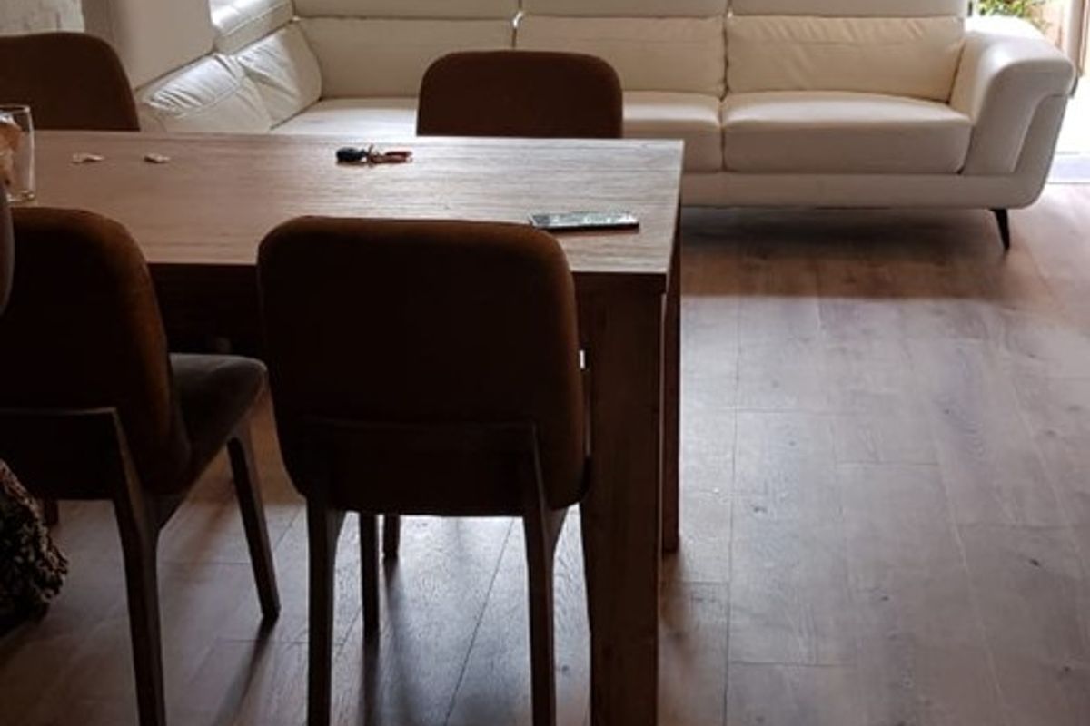 Open plan living and dining area featuring modern laminate flooring, exposed brick wall, and large sliding glass doors leading to an outdoor space.