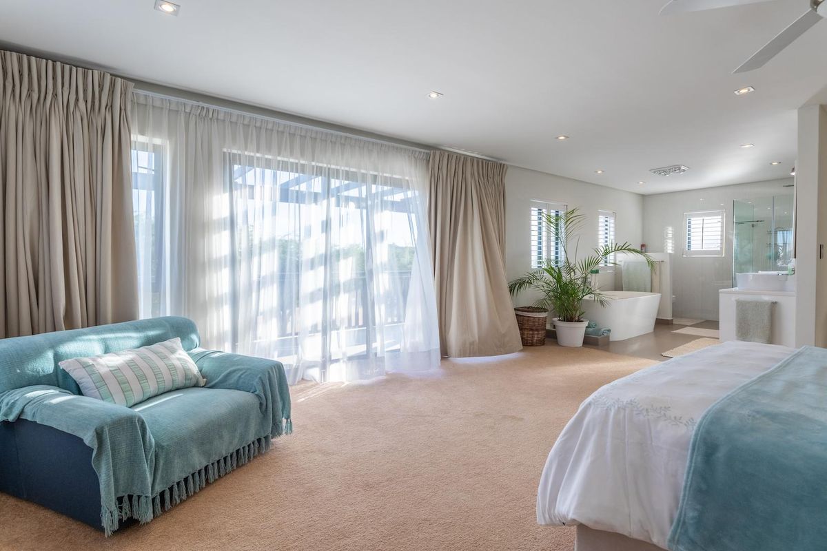 Spacious master bedroom suite featuring an open-plan layout, integrated en-suite bathroom with a soaking tub, and large sliding doors leading to a private balcony.