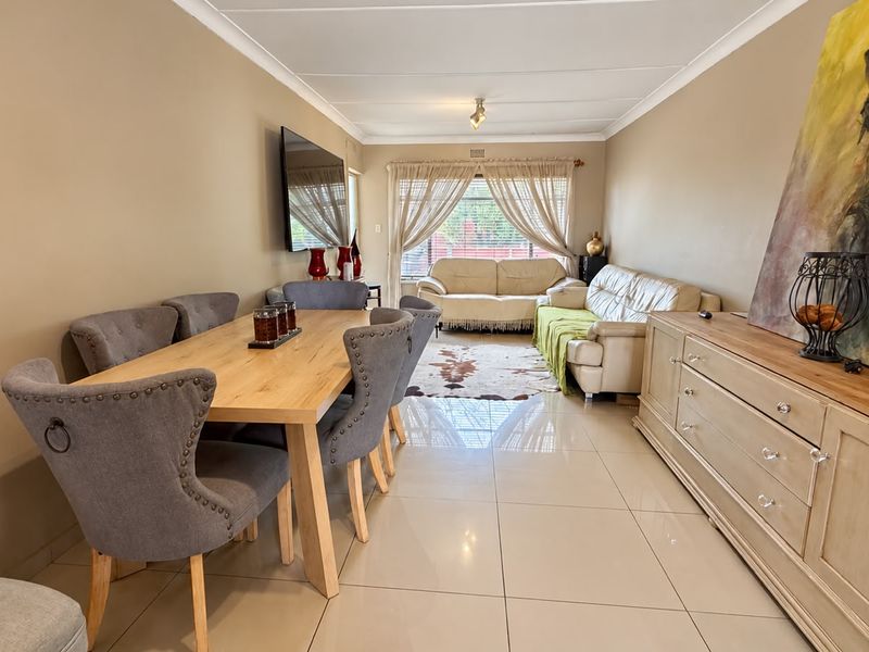 Spacious open-plan living and dining area featuring neutral tiled flooring and coved ceilings, providing a versatile layout for comfortable family living.