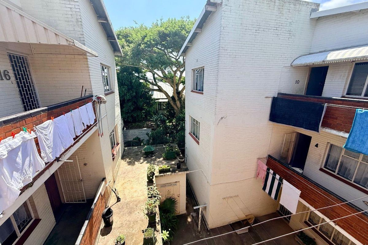 An elevated view of the apartment complex courtyard, featuring brick facade buildings, communal walkways, and a central outdoor area.