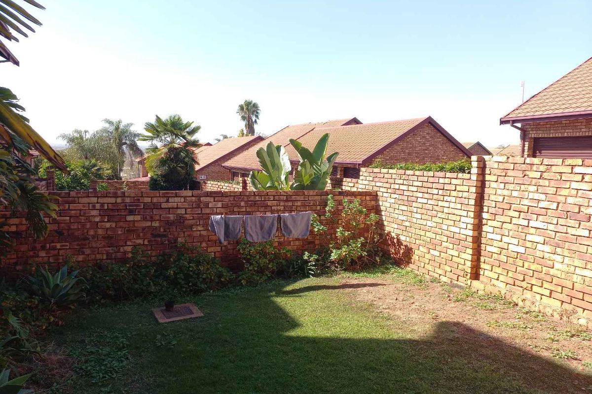 A private rear garden area featuring a brick boundary wall and a small lawn, providing a secure outdoor space for the apartment.