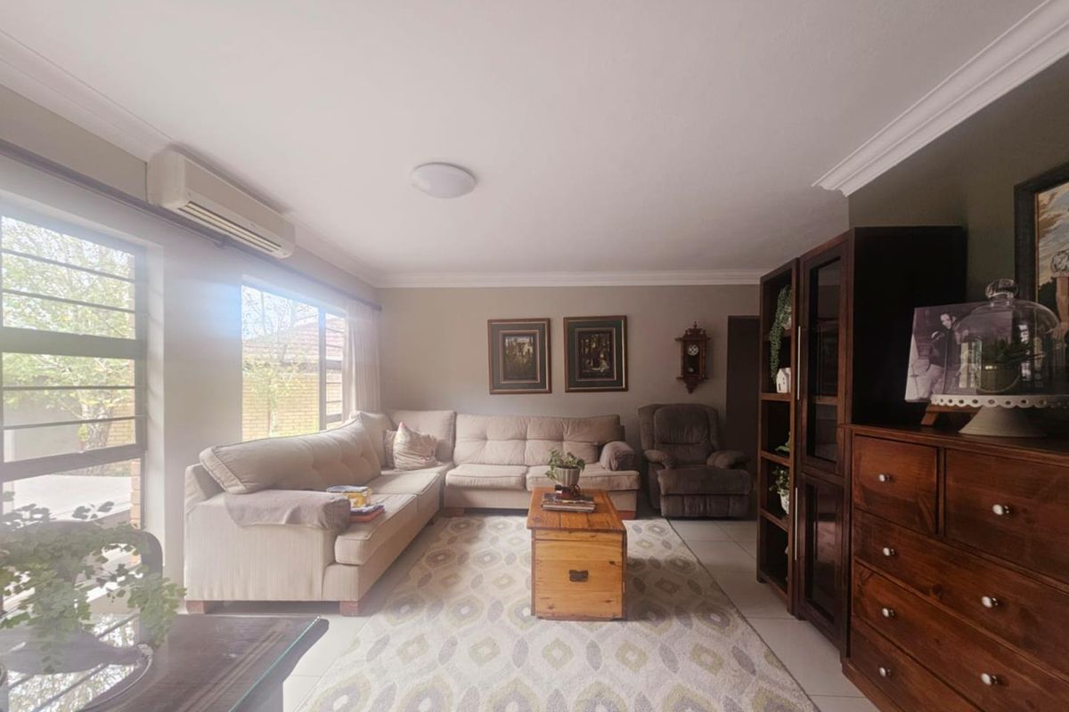 A comfortable living room featuring tiled flooring, crown molding, and a wall-mounted air conditioning unit.