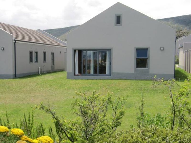 Rear view of a townhouse featuring a plastered facade, sliding glass doors, and a private lawn area.
