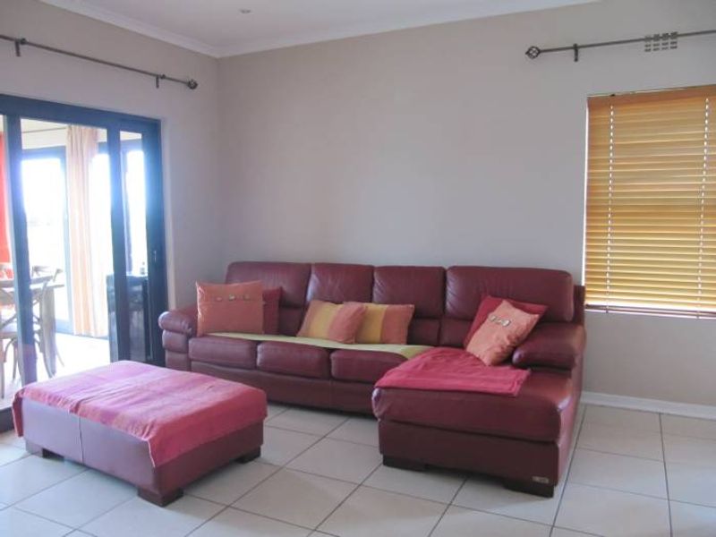 A living room featuring tiled flooring, a sliding glass door leading to an outdoor area, and venetian blinds on the window.