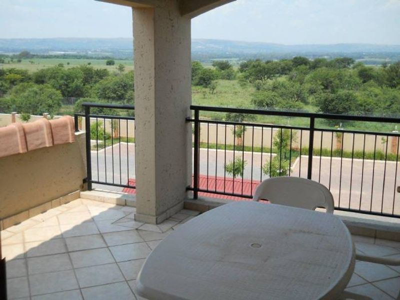 A covered balcony featuring tiled flooring and a metal balustrade, offering expansive views of the surrounding landscape.