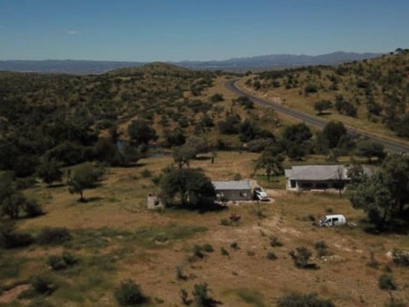 Aerial view of a rural farm property featuring multiple structures situated in a vast landscape with direct access to a main road.