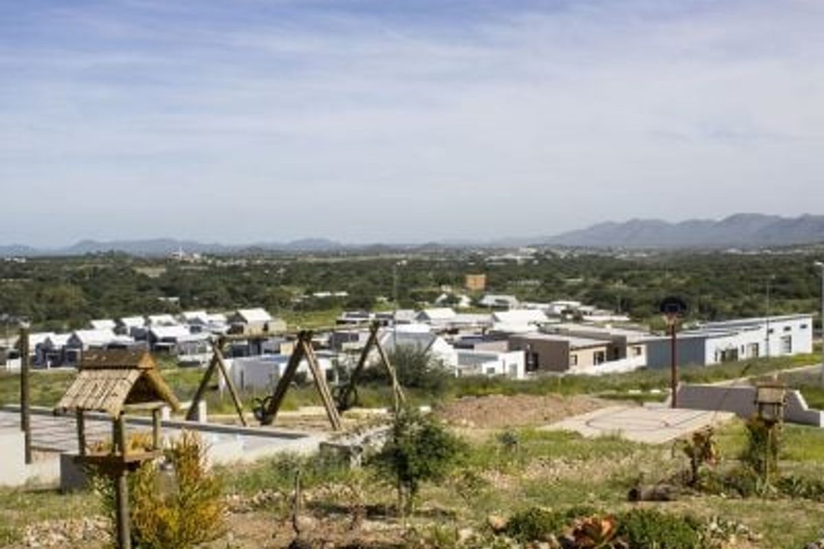 Elevated view overlooking a residential development with surrounding natural landscape and recreational features in the foreground.
