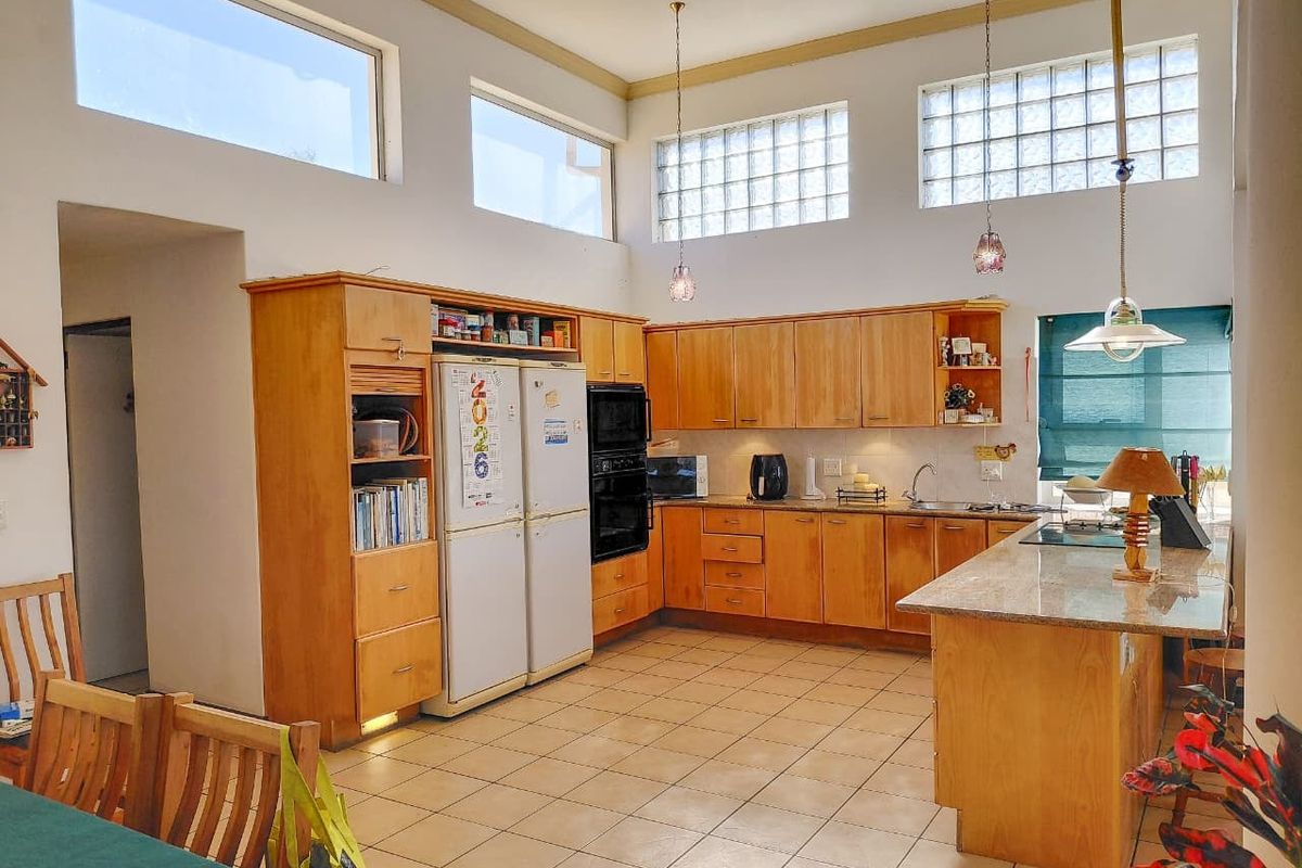 Spacious kitchen featuring wooden cabinetry, granite countertops, a central island, and high-level glass block windows providing ample natural light.
