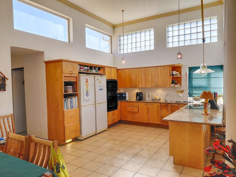 Spacious kitchen featuring wooden cabinetry, granite countertops, a central island, and high-level glass block windows providing ample natural light.
