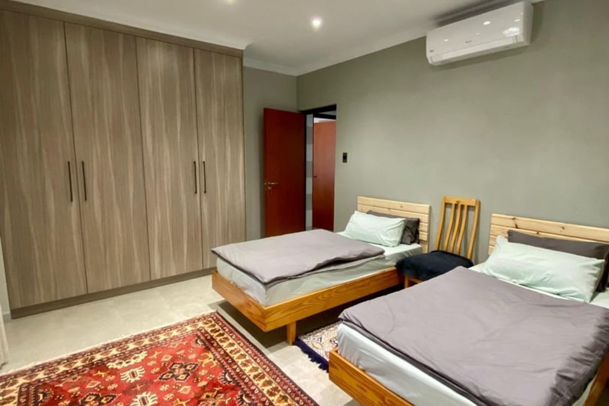 A well-maintained bedroom featuring built-in wooden cupboards, recessed ceiling lighting, and a wall-mounted split-system air conditioning unit.