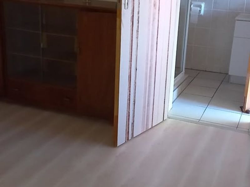 A bedroom featuring light-toned laminate flooring with direct access to an adjoining tiled bathroom.
