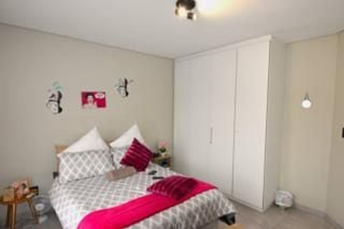 A well-maintained bedroom featuring a large built-in wardrobe, neutral wall finishes, and integrated lighting fixtures.
