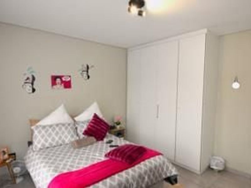 A well-maintained bedroom featuring a large built-in wardrobe, neutral wall finishes, and integrated lighting fixtures.