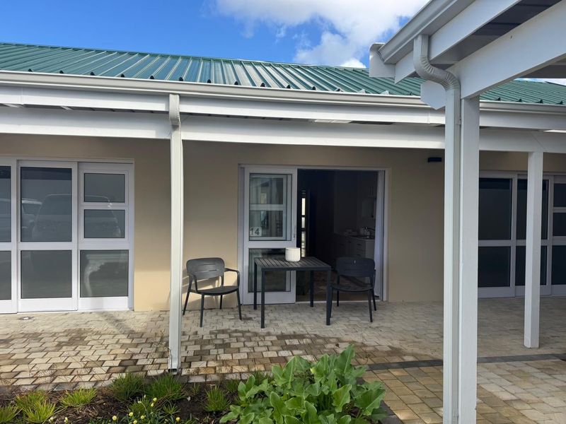 A covered patio area featuring paved flooring and direct access to the unit, providing a functional outdoor space for relaxation.
