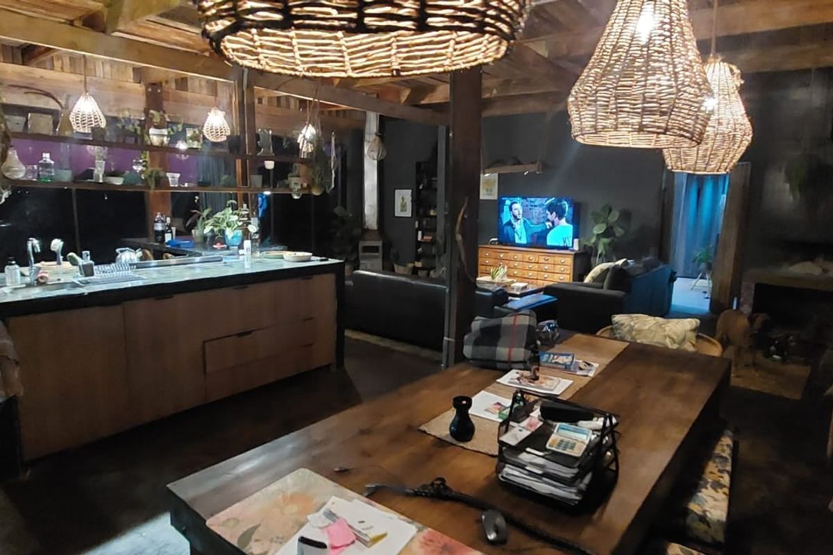 Spacious open-plan living area featuring a kitchen island, exposed timber beams, and a built-in fireplace, creating a warm and rustic lodge atmosphere.