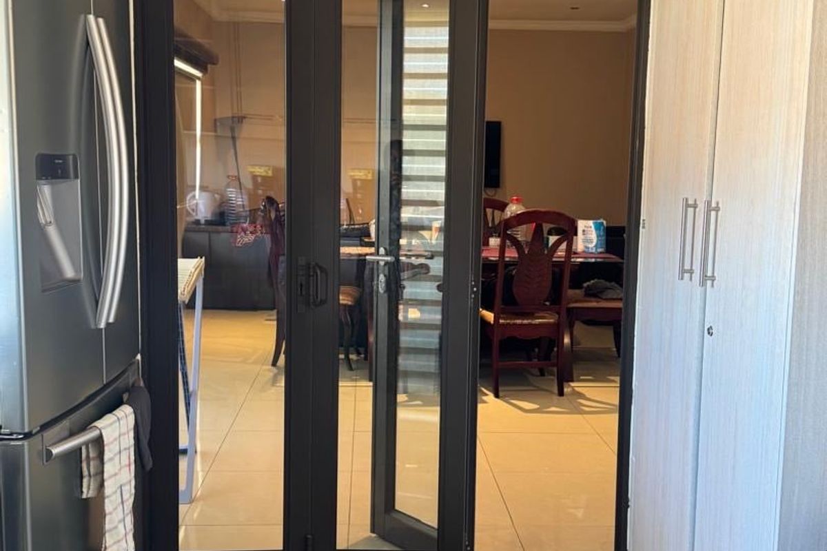 A functional kitchen area featuring modern built-in cabinetry and tiled flooring, with a glass-paneled door providing a clear view into the adjacent dining space.