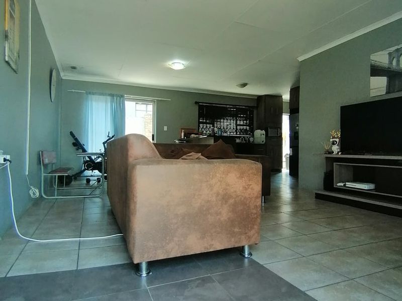 Open plan living area featuring tiled flooring and recessed lighting, flowing into a kitchen space with built-in cabinetry.