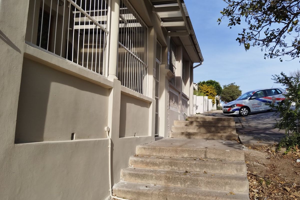 Exterior view of the property entrance featuring concrete stairs and security bars on the windows.