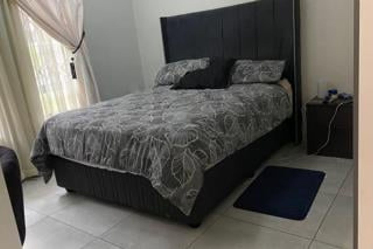 A bedroom featuring tiled flooring and a sliding glass door providing access to the exterior.