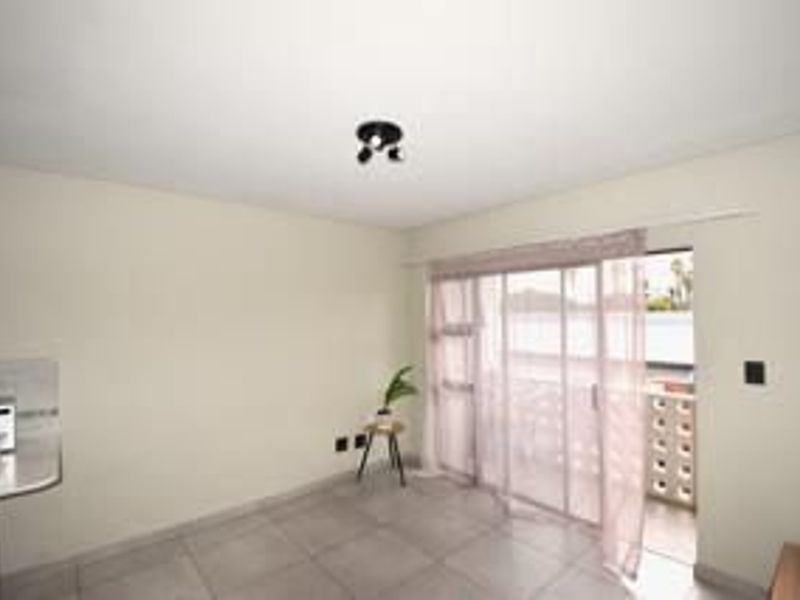 An open-plan living area featuring tiled flooring and a sliding glass door providing access to an outdoor balcony space.