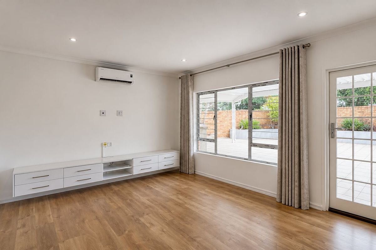 Bright living room featuring wood-look flooring, a wall-mounted air conditioning unit, built-in cabinetry, and direct access to an outdoor patio area.
