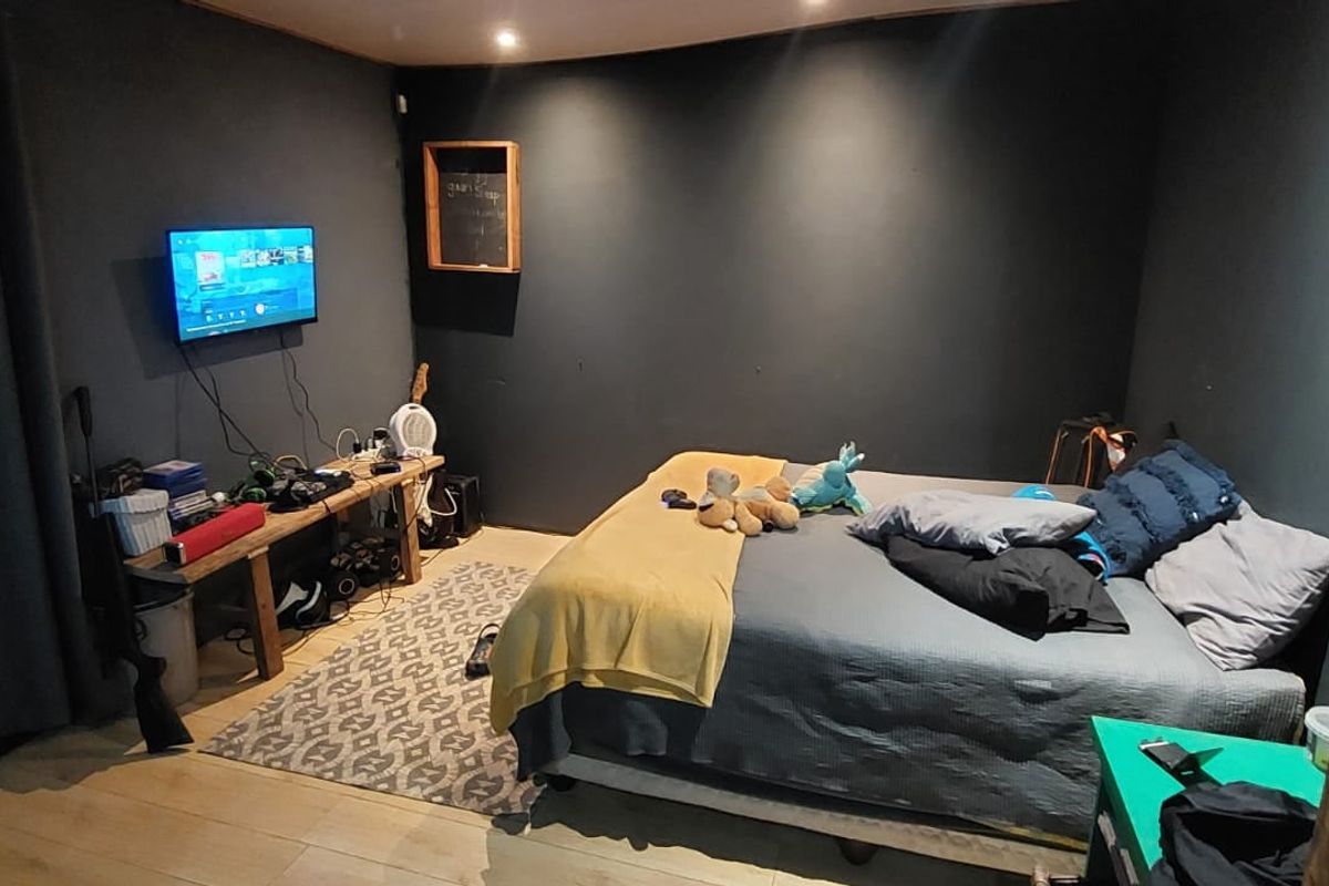 A bedroom featuring dark painted walls, recessed ceiling lighting, and light-toned laminate flooring.