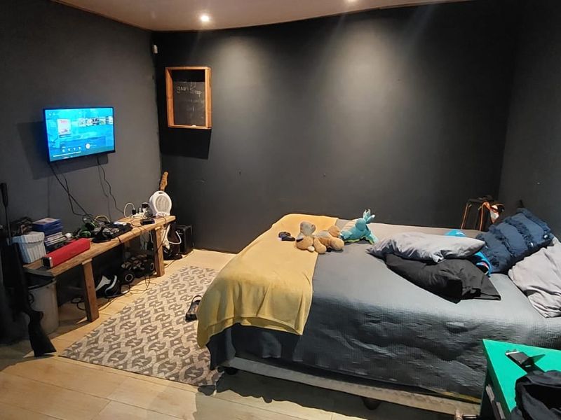 A bedroom featuring dark painted walls, recessed ceiling lighting, and light-toned laminate flooring.