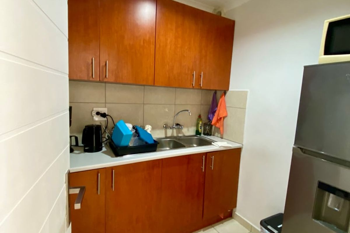 A functional scullery area featuring wooden built-in cabinetry, a double basin sink, and tiled flooring, providing practical utility space.