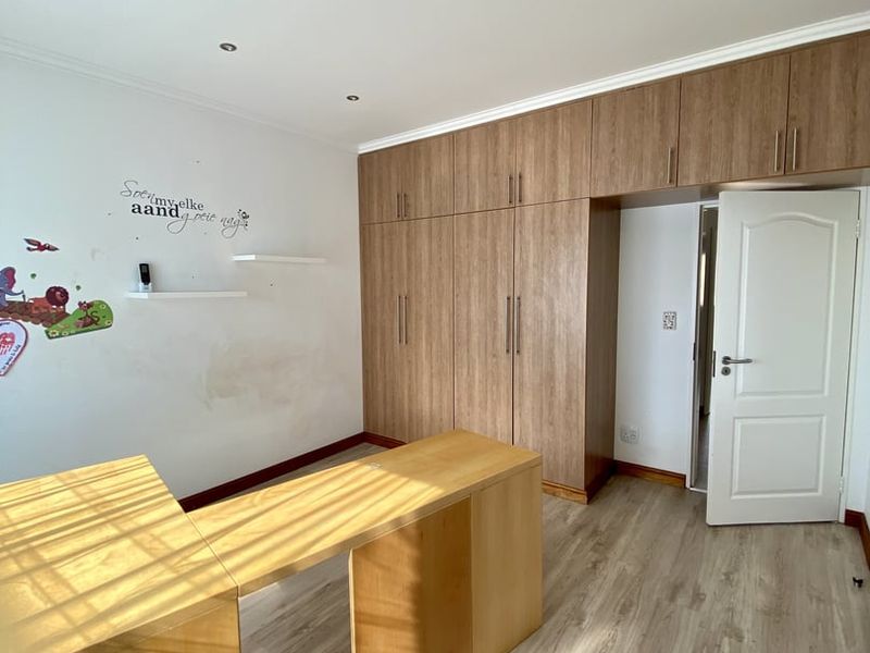 Bedroom featuring extensive built-in wooden cupboards, laminate flooring, and recessed lighting. The room offers ample storage space and a neutral layout.