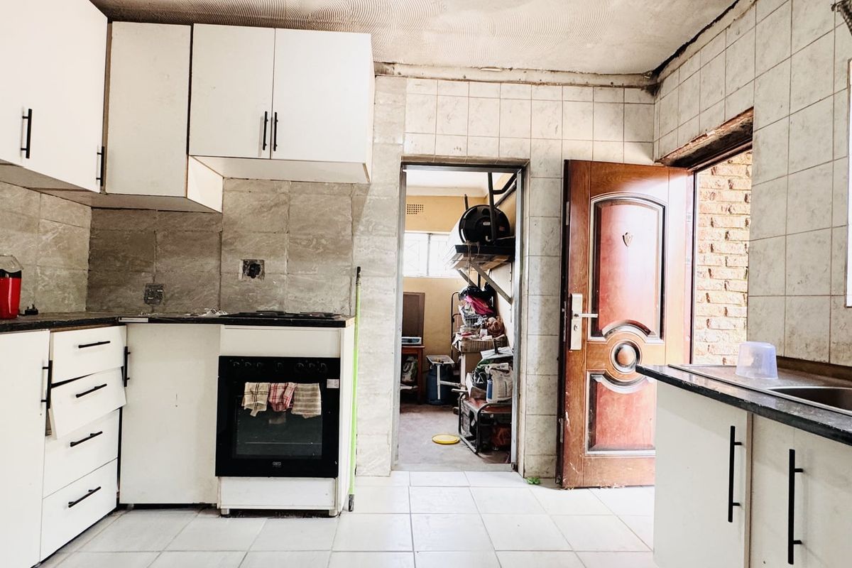 A dated kitchen featuring built-in cabinetry, an oven, and tiled finishes, requiring renovation to modernize the space and address visible wear.