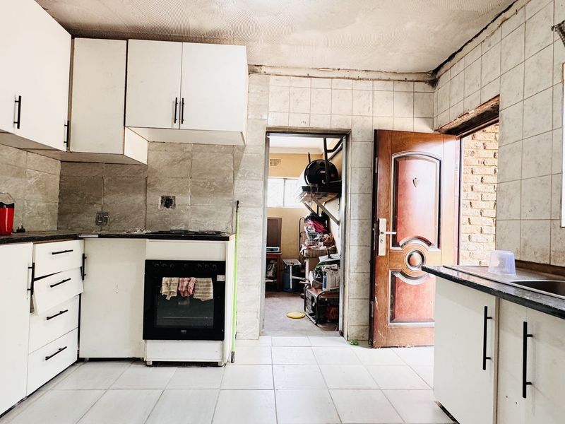 A dated kitchen featuring built-in cabinetry, an oven, and tiled finishes, requiring renovation to modernize the space and address visible wear.
