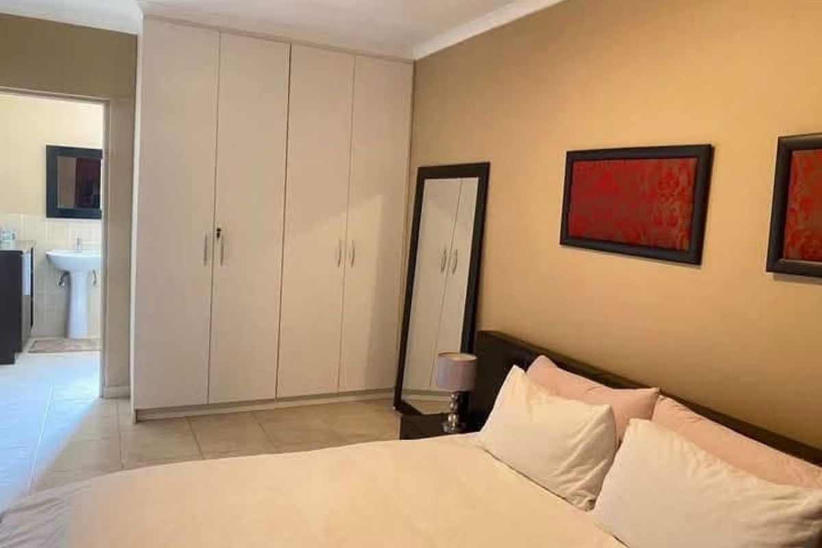 A bedroom featuring built-in cupboards, tiled flooring, and direct access to an en-suite bathroom.
