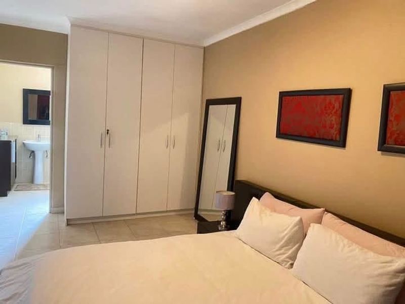 A bedroom featuring built-in cupboards, tiled flooring, and direct access to an en-suite bathroom.