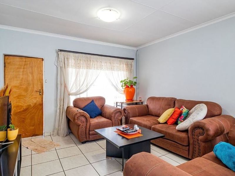A living room featuring tiled flooring and an exposed flue pipe, offering a functional space with potential for cosmetic updates.
