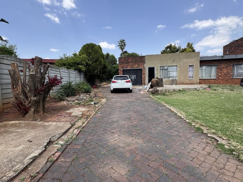 Front exterior view of the property featuring a brick paved driveway, precast boundary wall, and a single garage entrance.