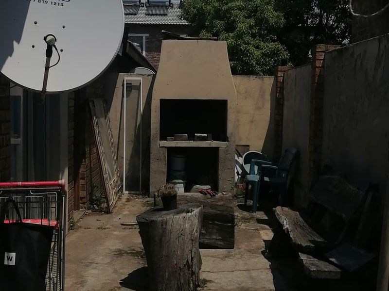 Outdoor patio area featuring a built-in braai, concrete paving, and brick boundary walls, offering a functional space for outdoor cooking and entertainment.